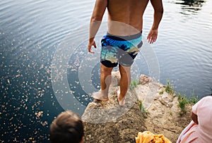 Young shirtless man ready to jump from a cliff into a lake