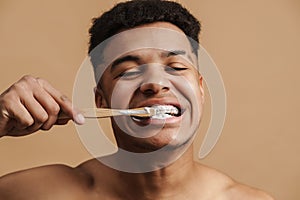 Young shirtless man smiling while brushing his teethes