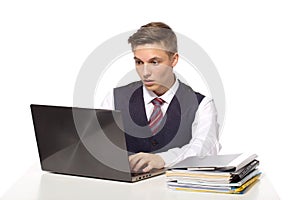 Young shocked businessman calculates taxes at desk in office. Isolated on white