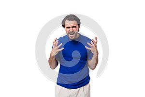 young shocked european brunette man with beard dressed in blue t-shirt on studio background