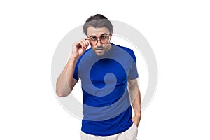 young shocked european brunette man with beard dressed in blue t-shirt on studio background