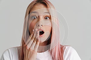Young shocked woman covering her mouth and looking at camera