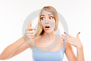 Young shocked woman looking at damaged split ends
