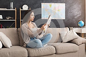 Young shocked woman reading newspaper