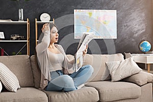 Young shocked woman reading newspaper