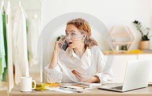 Young shop assistant talking on phone, discussing buyer`s order