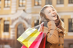 Young shopaholic woman. Beautiful young women holding the shopping bags in her hands and smiling at camera