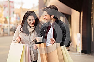 Young shopaholics looking into shopping bags outdoors