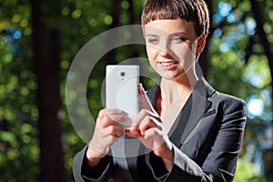 Young short hair woman taking a photo with her cell phone camera