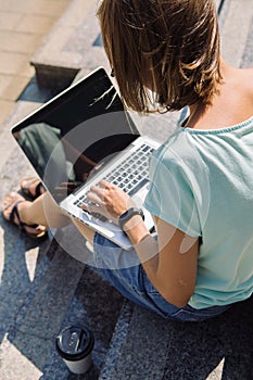 Young short-haired girl working on laptop in sunlight