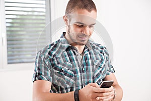 young short-haired man checks his smartphone smiling