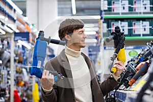 Young short-haired man chooses between pulverizers in shop