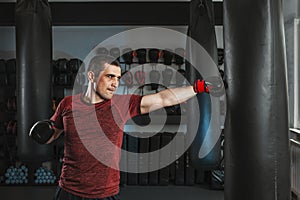 Young short-haired man is training in a gym with a punching bag