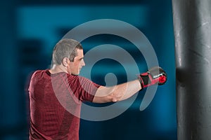 Young short-haired man is training in a gym with a punching bag