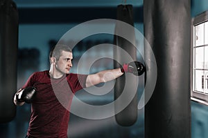 Young short-haired man is training in a gym with a punching bag