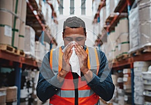 Young sick african warehouse worker blowing nose while working wearing safety vest