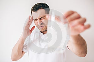 Young sick man isolated over background. Guy hold blurred glass with water and effervescent pills in it. Hold with