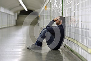 Young sick man lost suffering depression sitting on ground street subway tunnel