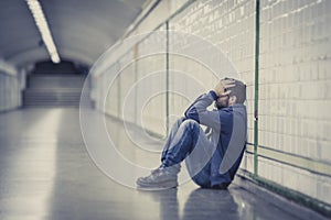 Young sick man lost suffering depression sitting on ground street subway tunnel