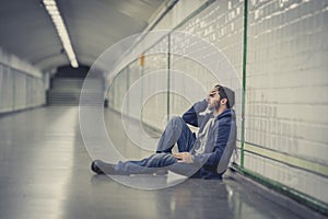 Young sick man lost suffering depression sitting on ground street subway tunnel