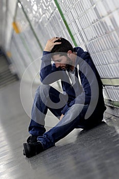 Young sick man lost suffering depression sitting on ground street subway tunnel