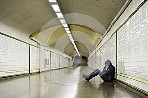 Young sick man lost suffering depression sitting on ground street subway tunnel