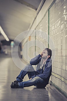 Young sick man lost suffering depression sitting on ground street subway tunnel