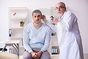 Young sick man visiting old doctor otolaryngologist