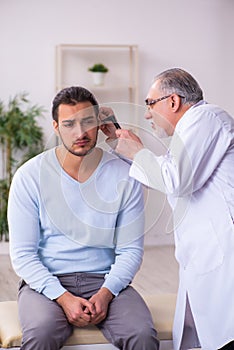 Young sick man visiting old doctor otolaryngologist