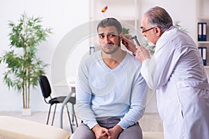 Young sick man visiting old doctor otolaryngologist