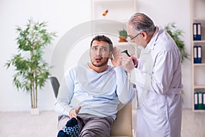 Young sick man visiting old doctor otolaryngologist