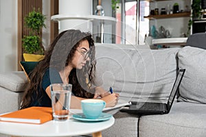 Young sick schoolgirl or student girl doing online homework or educational exam for college, using laptop computer. Ill teenager