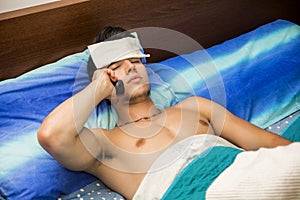 Young sick or unwell man in bed calling doctor photo