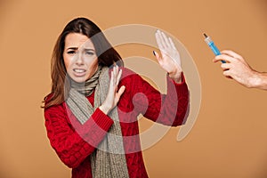 Young sick woman afraid of injection, looking at camera