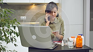 Young sick woman calling a doctor to get an online consultation during her illness at home. Telemedicine