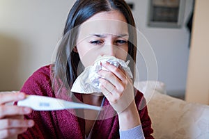 Young sick woman with cold and flu she is blowing her nose
