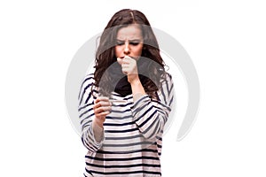 Young sick woman coughs in scarf and home clothes looking at thermometer.