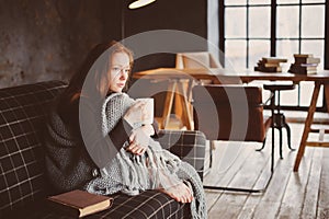 Young sick woman healing with hot drink at home on cozy couch