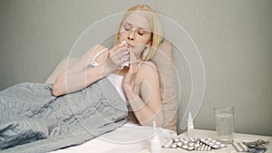 .Young sick woman sneezing at home at night on the couch. Girl runny nose and holding tissue, flu symptoms