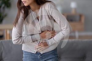 Young sick woman standing holding belly suffering from stomach pain