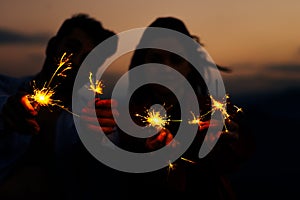 Young silhouette couple having fun with some firecracker at mountain