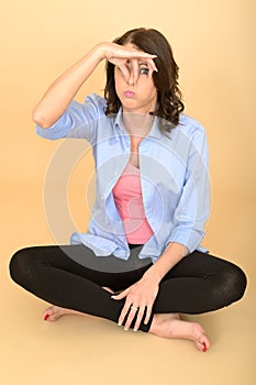 Young Silly Attractive Woman Sitting on the Floor Holding Nose