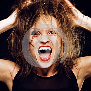 Young silly crazy girl with messed hair making stupid faces on black background, lifestyle people concept