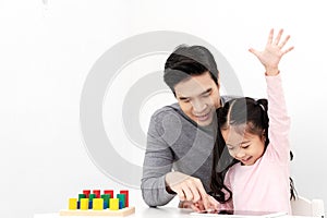 Young single dad play smart gadget and have fun with daughter sitting on kid desk table with colorful block toy beside copy space