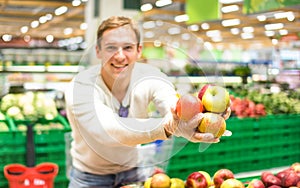 Young single man showing fruit and vegetables at shopping in grocery store supermarket - Modern healthy lifestyle concept concept