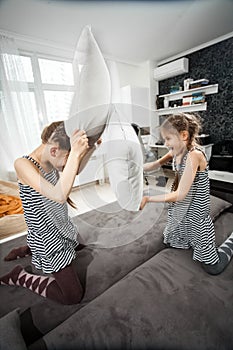 Young sisters pillow fighting on couch