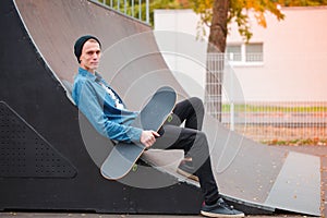 Young skatebarder posing with skateboard in the skatepark. Sport concept.