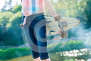 Young skateboard girl holding her longboard outdoors on sunset
