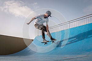 Young skateboarder flies with his board on the ramp of a skate park
