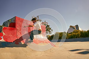 Young skateboarder flies with his board on the ramp of a skate park